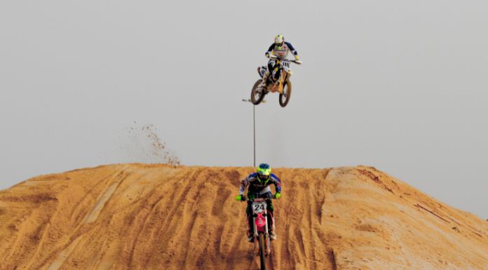 2 men on motocross, the other is jumping off his dirt bike